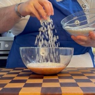 Versamento del riso crudo (varietà Arborio o Roma) direttamente nel condimento di pomodoro speziato.