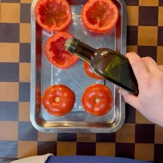 Farcitura manuale del pomodoro con il mix di riso marinato utilizzando un cucchiaio da cucina.