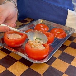 Dettaglio del pomodoro riempito di riso fino a un centimetro dal bordo, pronto per la cottura al forno.