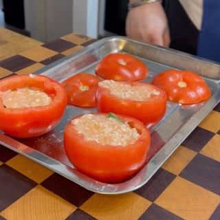 Posizionamento del 'cappello' tagliato in precedenza sopra il pomodoro ripieno di riso saporito.