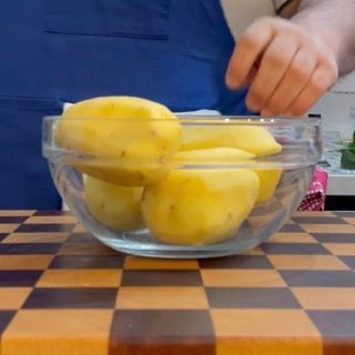 Sbucciatura manuale delle patate a pasta gialla con un pelapatate, base per il contorno al forno.