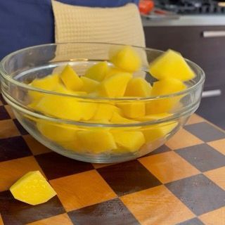 Versamento del condimento di pomodoro tenuto da parte sugli spicchi di patate nella ciotola.