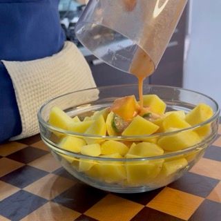 Aggiunta di aghi di rosmarino fresco e olio evo generoso sulle patate da cuocere al forno.
