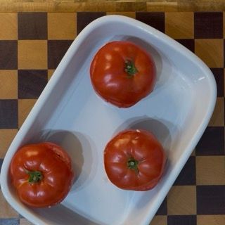 Posizionamento distanziato dei pomodori ripieni di riso in una grande teglia da forno oliata.