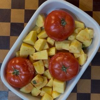 Teglia completa e ordinata con pomodori con riso e patate al forno pronti per l'infornata.