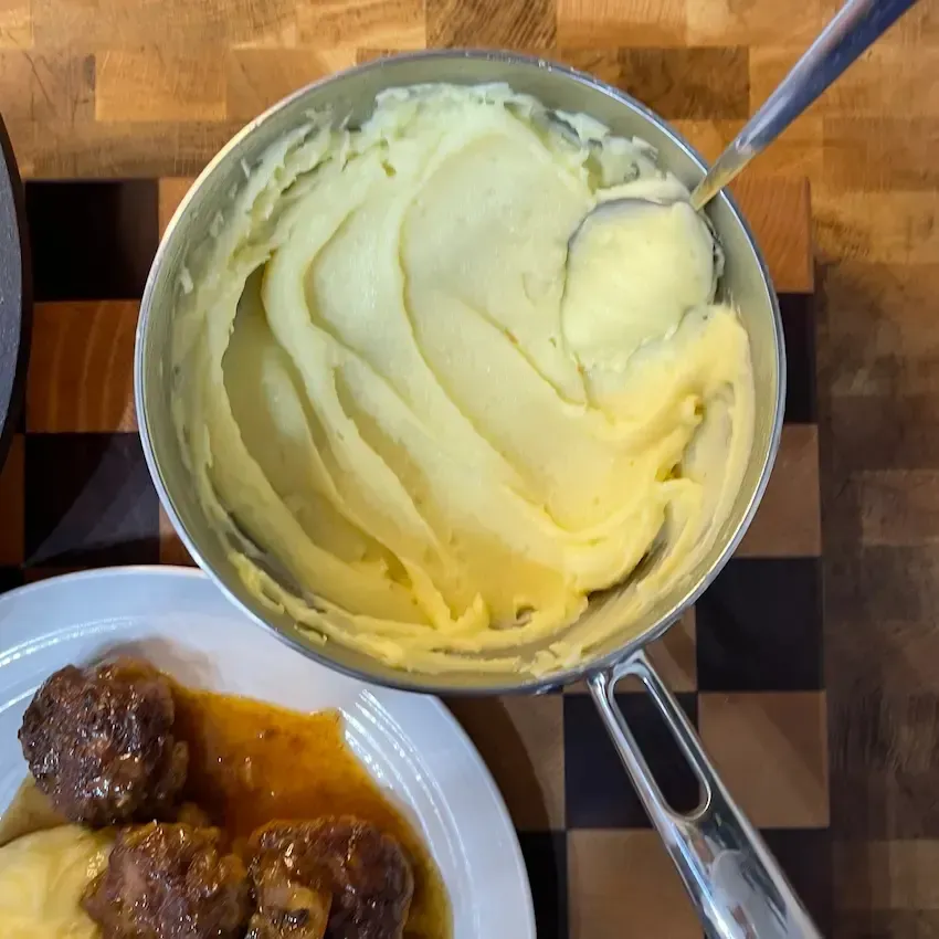 Un tegame con purè di patate cremoso e senza grumi, lavorato con lo schiacciapatate e mantecato con