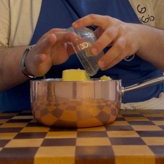 Aggiunta del burro freddo a cubetti sulla patata setacciata per il purè di patate con latte e burro.