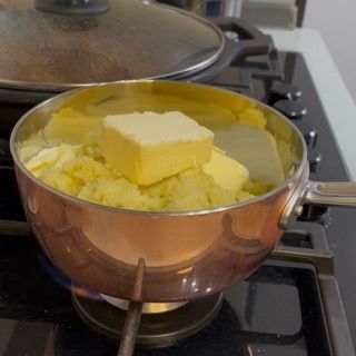 Mantecatura con frusta a mano sul fuoco per sciogliere il burro nella patata del purè.