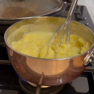 Aggiunta della seconda metà di latte caldo per completare la struttura del purè di patate.