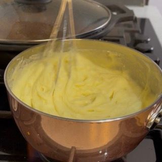 Rimozione della pentola dal fuoco con la crema di patate calda perfettamente assorbita.