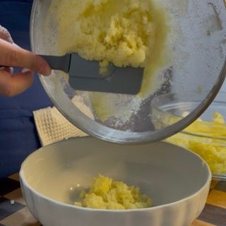 Trasferimento della patata setacciata all'interno di una pentola capiente per la cottura.