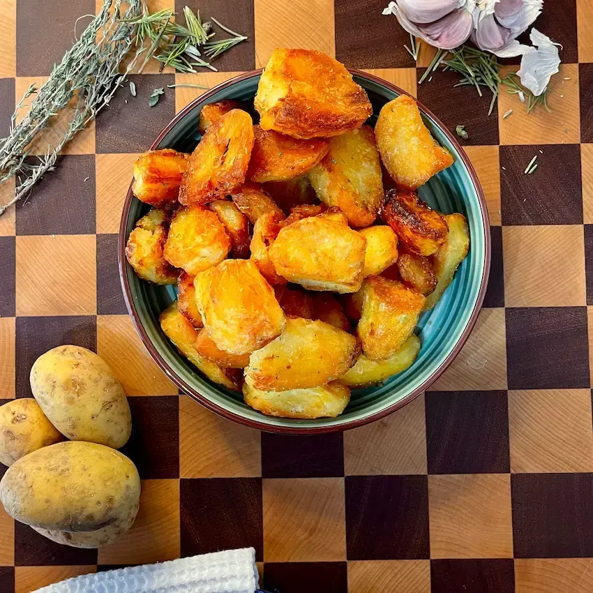 Patate al forno croccanti e dorate in un piatto, condite con rosmarino fresco e sale grosso.