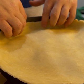 Il disco di pasta brisée adagiato sopra i carciofi in padella
