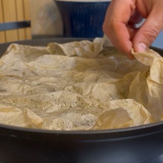 Disco di carta da forno posizionato sopra i carciofi per una cottura uniforme