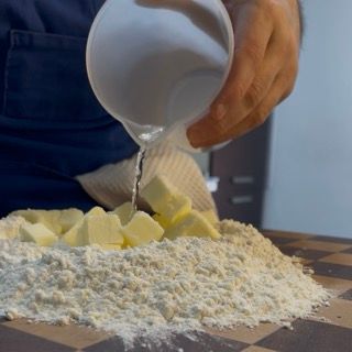 Mani che lavorano velocemente burro e farina (sabbiatura)