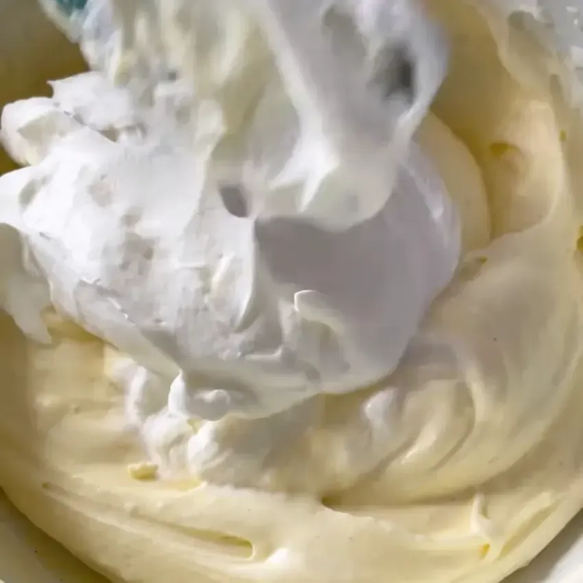 Panna fresca montata a neve ferma in una ciotola di vetro.