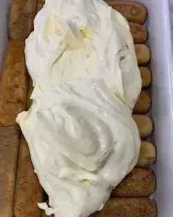 ssemblaggio del tiramisù classico con il primo strato di crema al mascarpone spalmata sui savoiardi.