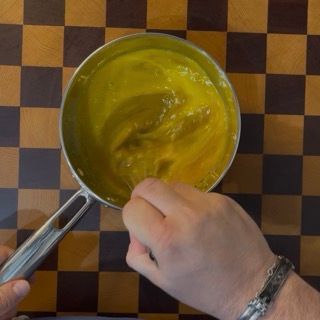Versamento di tuorli, zucchero, acqua e vaniglia nel pentolino per la pastorizzazione delle uova.