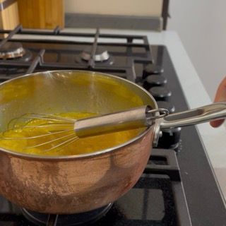 Cottura a fiamma media del composto di tuorli fino a 75 gradi per una torta tiramisù senza uova crude.