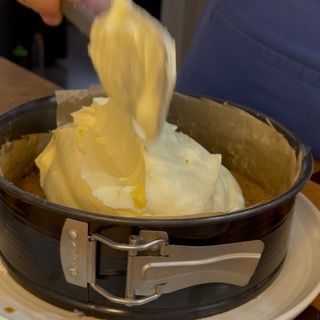 Versamento del primo strato di crema al mascarpone sul disco di savoiardo imbevuto di caffè.