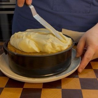 Sagomatura della cupola di crema al mascarpone sulla superficie della torta tiramisù facile.