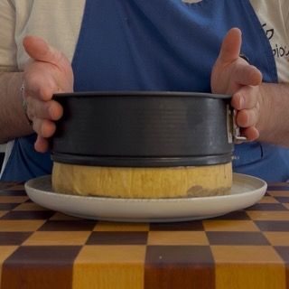 Rimozione delicata dell'anello d'acciaio dalla torta tiramisù moderna dopo il riposo in frigo.