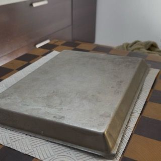Versamento di un cucchiaio di cioccolato fuso sul retro di una teglia tenuta in freezer.