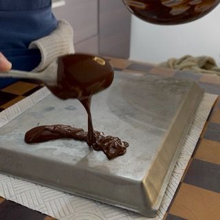 Stesura rapida del cioccolato fuso con la spatola per creare un velo sottilissimo e flessibile.