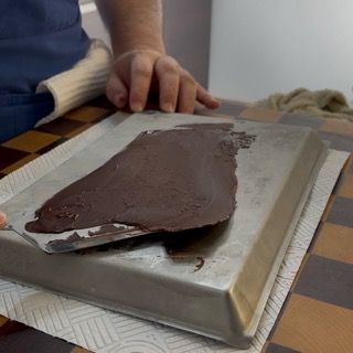 Stacco del velo di cioccolato flessibile dalla teglia congelata usando la spatola da pasticceria.