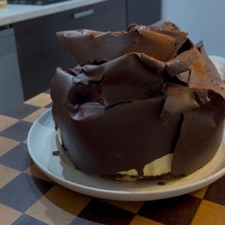 Spolverata abbondante di cacao amaro in polvere sulla decorazione di cioccolato del tiramisù.
