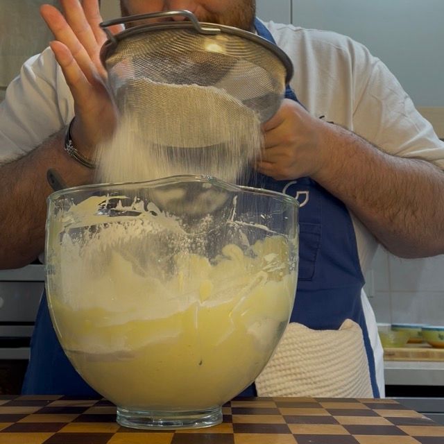 Farina e fecola setacciate direttamente sull'impasto spumoso.