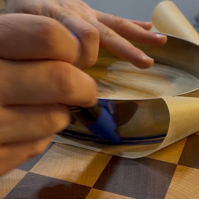 Disegno delle linee guida da 22 cm sulla carta da forno per formare i dischi di biscotto savoiardo.