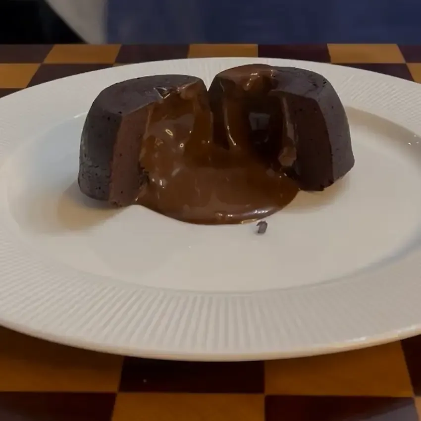 Tortino al cioccolato dal cuore caldo e morbido con colata di cioccolato fondente fuso al taglio del cucchiaino.
