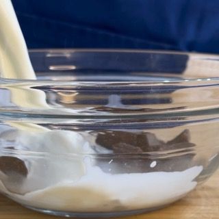 Scioglimento del cioccolato fondente con panna calda per il cuore del fondant.