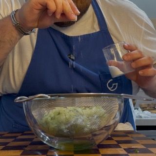 Riposo dei cetrioli nel colino coperti per un'ora, passaggio chiave per capire come fare lo tzatziki cremoso.