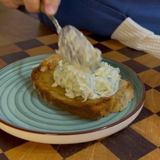 Spalmatura di uno strato abbondante di salsa tzatziki ricetta sul crostone di pane caldo e croccante.