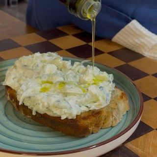 Crostone rustico completato con tzatziki cremoso e un filo d'olio, idea sfiziosa su cosa mangiare con tzatziki.