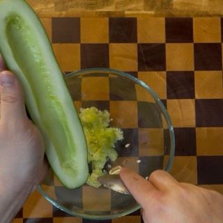 Utilizzo di una grattugia a fori larghi per sminuzzare i cetrioli freschi per gli tzatziki ingredienti perfetti.
