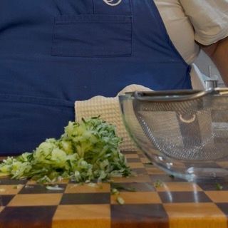 Trasferimento della polpa di cetriolo in un colino a maglia fine per iniziare la tzatziki ricetta greca.