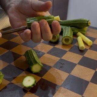 Taglio delle estremità e divisione a metà delle zucchine chiare per preparare le zucchine ripiene di carne.