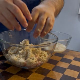 aggiunta del pane morbido strizzato alla carne macinata per preparare le zucchine ripiene ricetta della nonna.