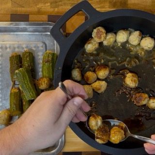 Rimozione attenta delle zucchine cotte e delle polpettine dal tegame usando una pinza da cucina.