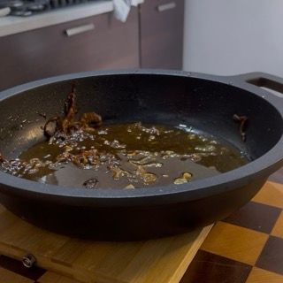 Taglio in quarti di pomodori ciliegino freschi da aggiungere al fondo di cottura delle zucchine di carne.