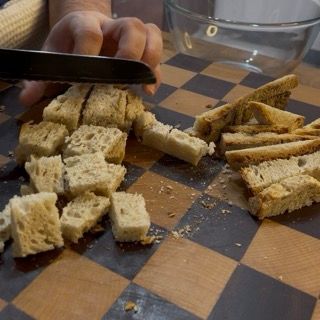 Taglio della mollica di pane a cubetti per la ricetta originale delle zucchine ripiene alla romana tradizionali.