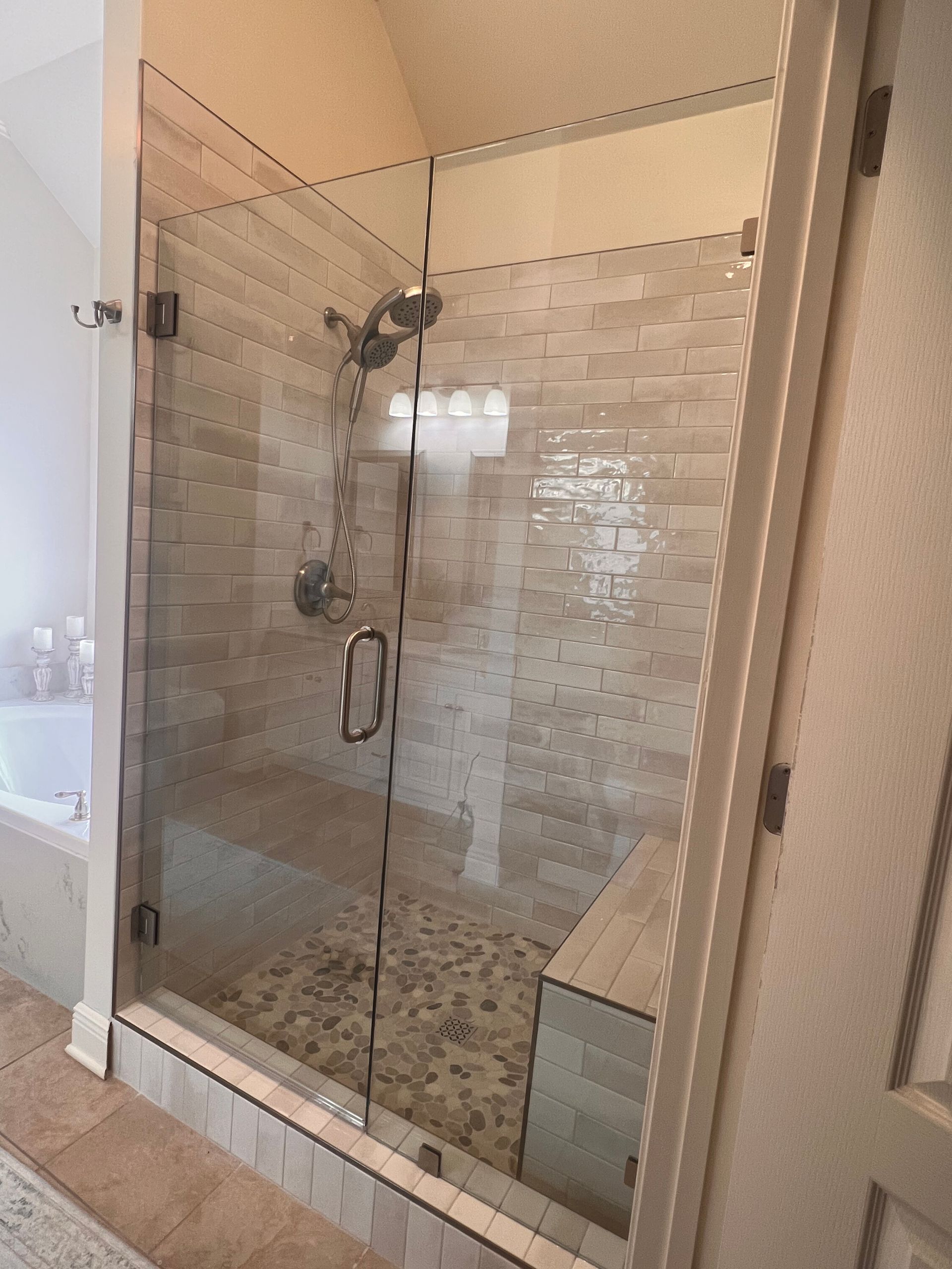 Glass shower stall with tiled walls and built-in bench in a bathroom
