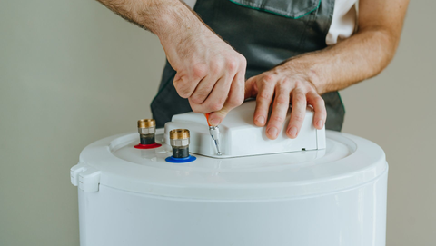 Hands placing a white device on top of a white cylinder, with wires and connectors visible
