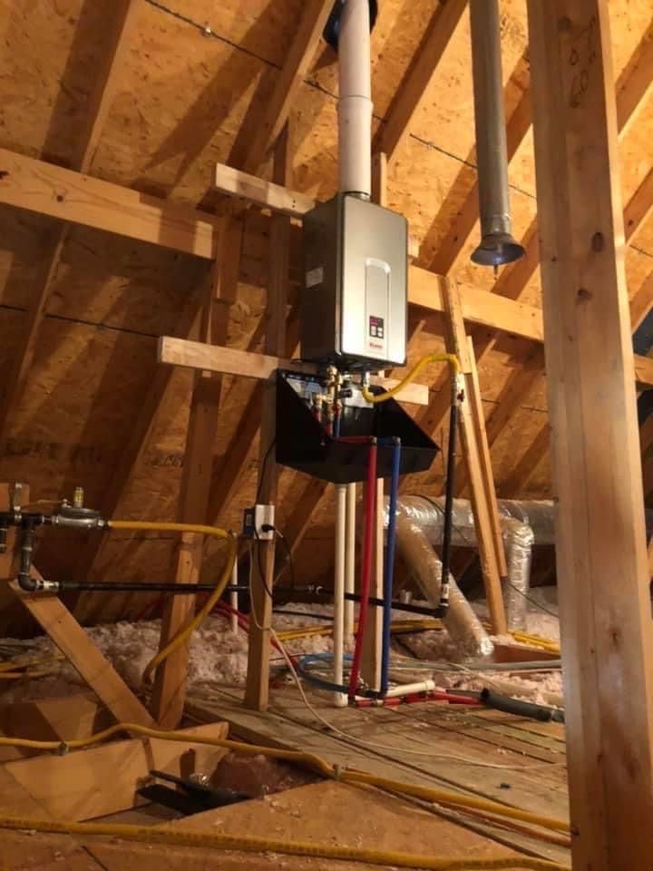 Unfinished attic with exposed framing, furnace and ductwork, and a central HVAC unit under installation.