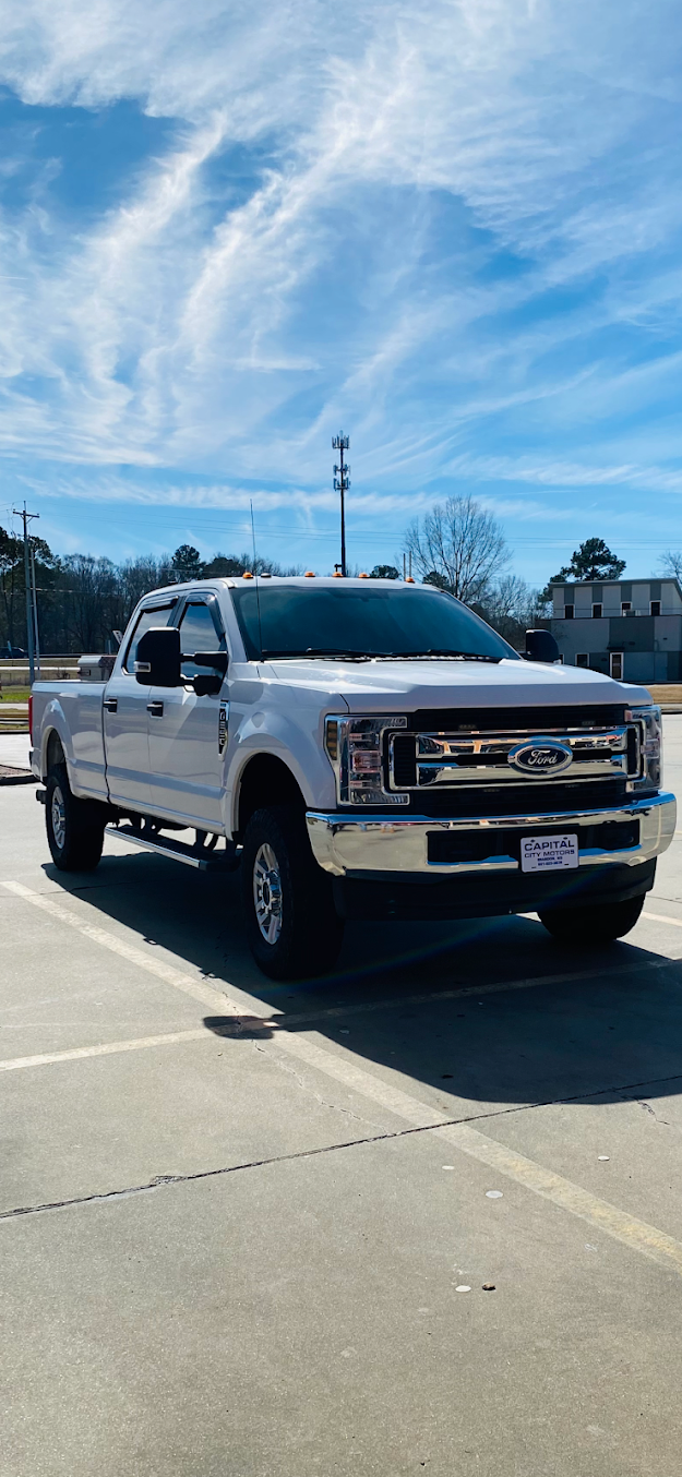 White pickup truck parked on a sunny lot under a blue sky