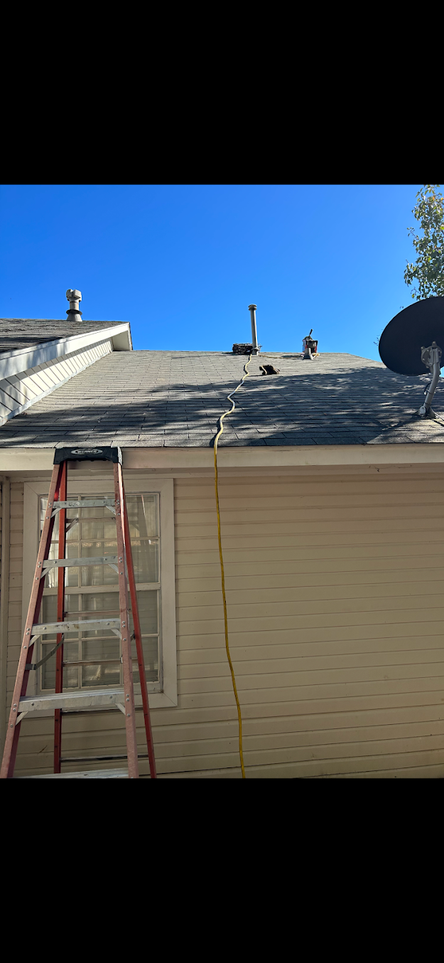 Roofers on a house roof with a red ladder leaning against the side under a blue sky