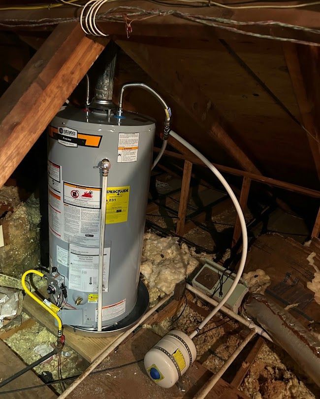 Water heater and pipes in a cluttered attic with exposed insulation and beams